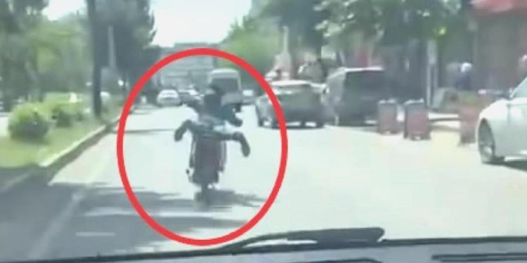 Motosikleti akan trafikte, üzerine yüzüstü yatarak kullandı